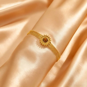 Gros plan sur un bracelet en maille dorée avec motif soleil et pierre œil-de-tigre