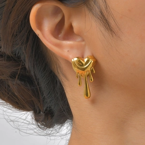 Gros plan sur la boucle d'oreille cœur liquide doré portée pour montrer l'éclat