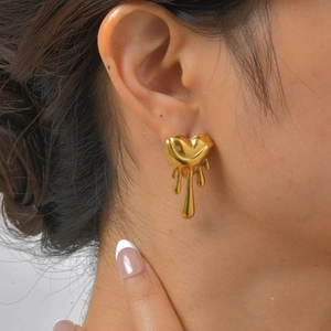 Gros plan d'une boucle d'oreille cœur doré effet liquide portée par un mannequin