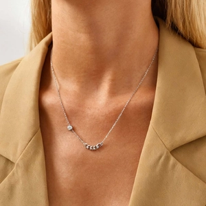 Minimalist silver stainless steel necklace with round zircon pendant on model in beige suit