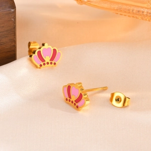 Gros plan de boucles d'oreilles couronne dorées avec cœur rose sur soie champagne