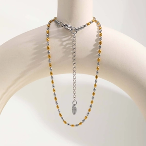 Detail van tweekleurige kralenketting met karabijnsluiting en gegraveerd S.S stalen label