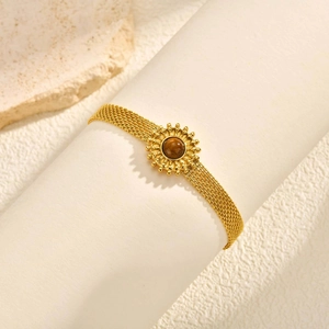 Bracelet doré à mailles avec pendentif soleil et pierre œil de tigre sur support blanc