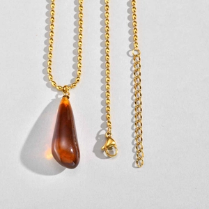 Detailed macro view of the amber waterdrop resin pendant and gold ball chain necklace