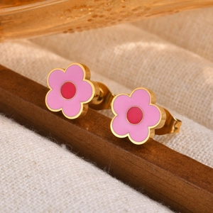 Boucles d'oreilles fleurs roses et or avec centre rouge sur fond élégant