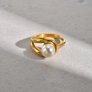 Detail of 18K gold stainless steel ring with elegant white pearl and crossed band