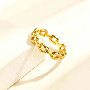 Detailed view of a gold chain ring with polished finish on a light stone surface