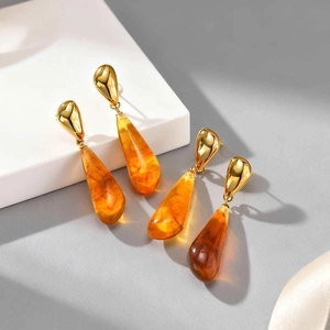 Detailed close-up of water drop resin earrings with amber texture and gold hooks