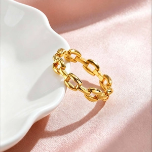 Detailed view of a gold chain ring on a white shell plate with pink silk fabric background