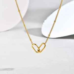 Macro detail of gold-plated paperclip link necklace with bead chain and geometric pendant