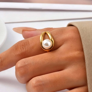 Close-up of golden stainless steel teardrop ring with a lustrous white pearl on finger