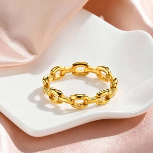 Close-up of golden Cuban link chain ring on a white decorative ceramic dish