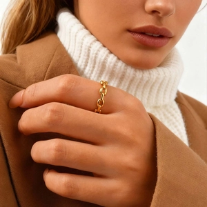 Detail of a gold chain link ring worn by a model in elegant autumn clothing