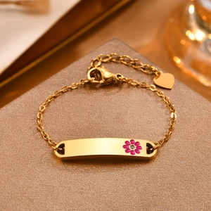 Detail of gold-plated bracelet featuring a pink enamel flower and a heart charm
