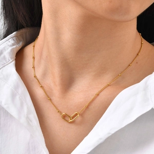 Close-up of minimalist interlocking paperclip chain necklace with gold beads on a model