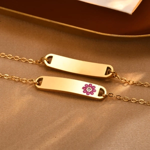 Close-up of golden stainless steel ID bracelets with a purple flower charm and zircon