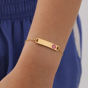 Close-up of gold stainless steel bracelet with rectangular plate and pink enamel flower