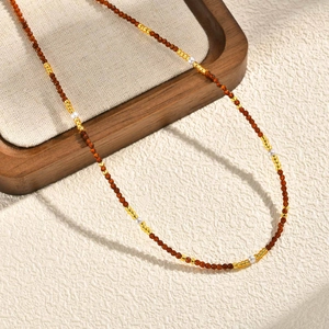 Dettaglio di collana vintage con perle marroni sfaccettate e perle sintetiche