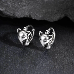 Detailed macro shot of vintage fox head earrings on textured black stone background