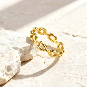 Polished gold stainless steel chain link ring on natural stone background