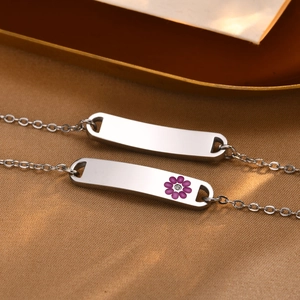 Close-up of customizable stainless steel ID plate bracelets with purple flower detail