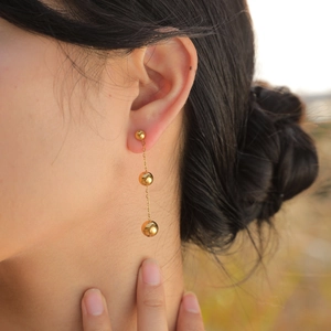 Elegant gold stainless steel drop earrings with bead tassels worn by a model