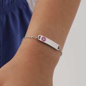 Close-up of a silver stainless steel bracelet with a pink flower charm on a wrist