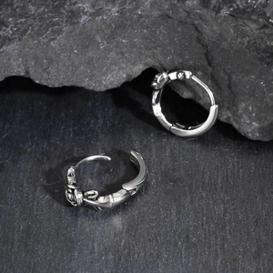 Macro detail of silver earring with gothic rose relief on dark stone background