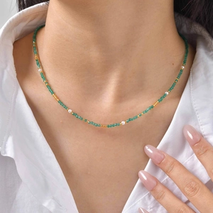 Dettaglio collana con perline verde smeraldo, perle bianche e accenti dorati