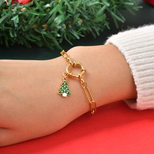 Détail d'un bracelet en chaîne trombone dorée avec un pendentif sapin de Noël vert