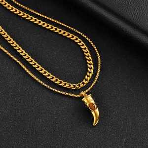 Dettaglio della collana doppia dorata con catena cubana e ciondolo in pietra occhio di tigre