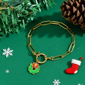 Détail du bracelet doré avec pendentif couronne de Noël sur un fond festif vert foncé