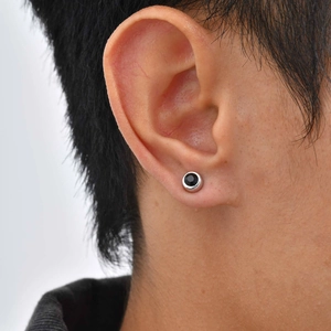 Macro shot of minimalist silver clip-on earring with black zircon stone on ear