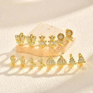 Détail de créoles dorées en laiton avec breloques en zircone cubique aux motifs variés