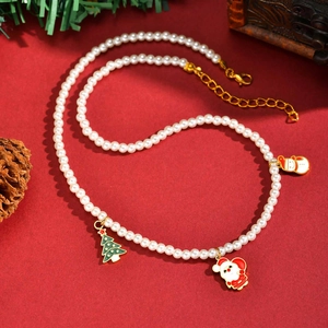 Vue macro du collier de perles de Noël avec pendentifs Père Noël sur fond rouge festif