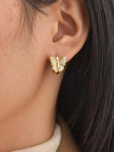 Gros plan d'une boucle d'oreille papillon dorée avec micro-pavé de zircons blancs