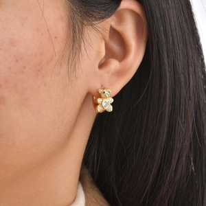 Vue rapprochée de la boucle d'oreille ours doré avec zircon cœur sur l'oreille
