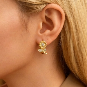 Détail macro d'une boucle d'oreille tournesol dorée avec pierre centrale et feuilles