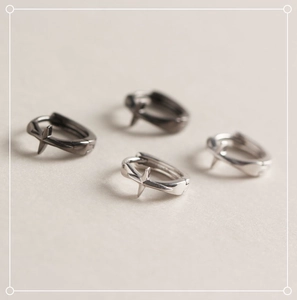 Vue macro de boucles d'oreilles étoile à croix minimalistes en argent avec détails polis