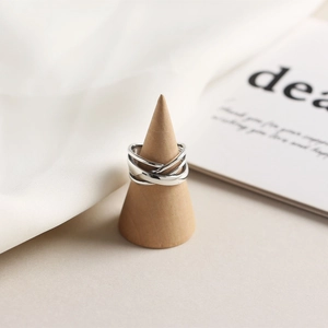 Macro shot of silver irregular layered winding ring on minimalist wood stand