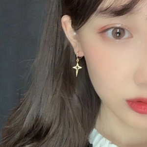Close-up of a model wearing a gold star-shaped hollow earring with a leverback clasp