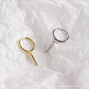 Macro shot of silver and gold triangle drop earrings with cubic zirconia on white paper