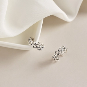 Detailed view of two s925 silver rings with retro woven texture on white silk fabric