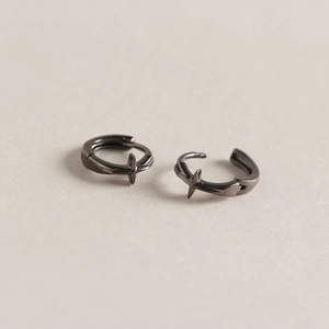 Vue macro de la boucle d'oreille croix noire avec finition polie et fermoir charnière
