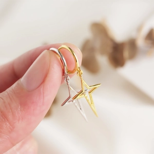 Detail of minimalist S925 sterling silver star huggie earrings in gold and silver finish