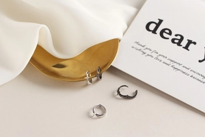 Détail de boucles d'oreilles en argent S925 et métal noir avec étoile sur plateau doré