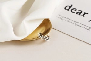 Detailed view of S925 sterling silver wavy triple-layer ring on a golden metal tray