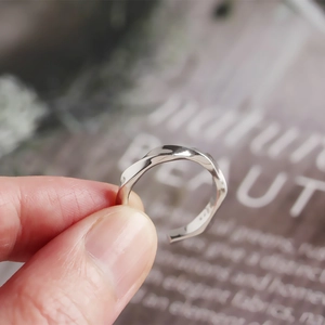 Macro detail of a twisted S925 sterling silver ring showing the modern Mobius loop texture
