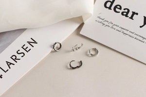 Gros plan de boucles d'oreilles croix noires et argentées sur soie et livre blanc