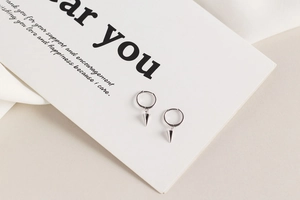 Close-up of S925 sterling silver geometric huggie earrings with a sharp cone pendant
